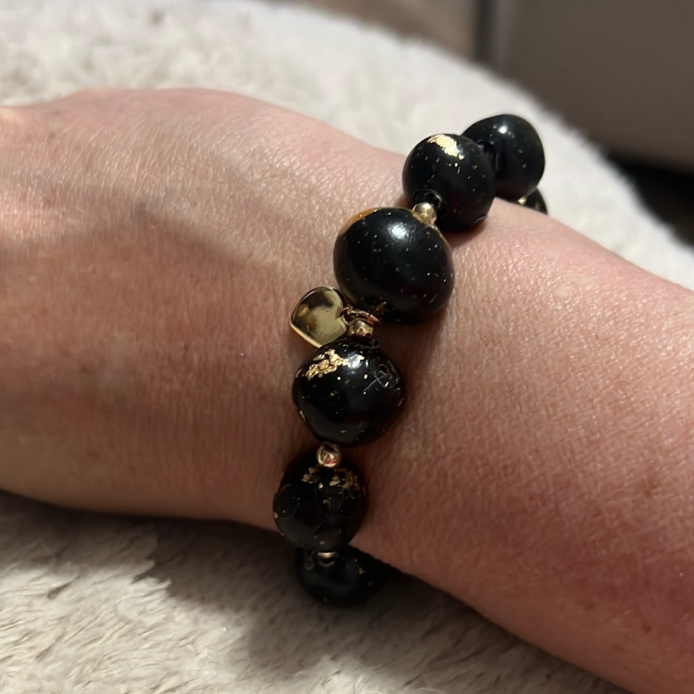 Black and gold homemade bracelet with a heart pendant.